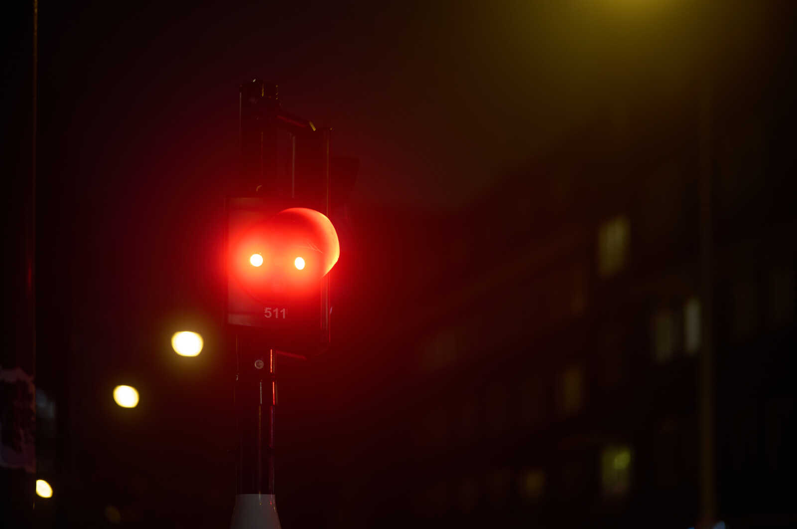A red traffic signal is centered in the frame. The signal has a white border and the number 511 is visible beneath the red light. It is mounted on a pole against a dark background.