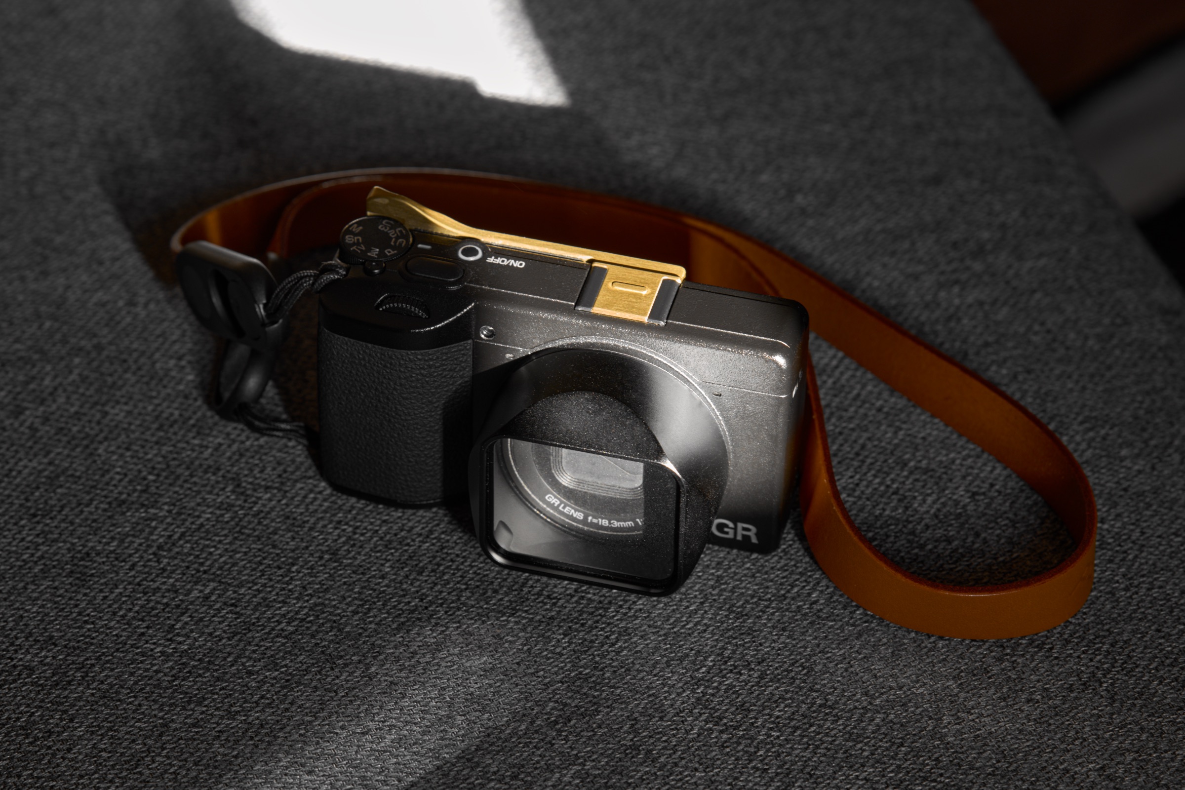 Ricoh GR IV camera with lens hood, thumb grip, and neck strap attached