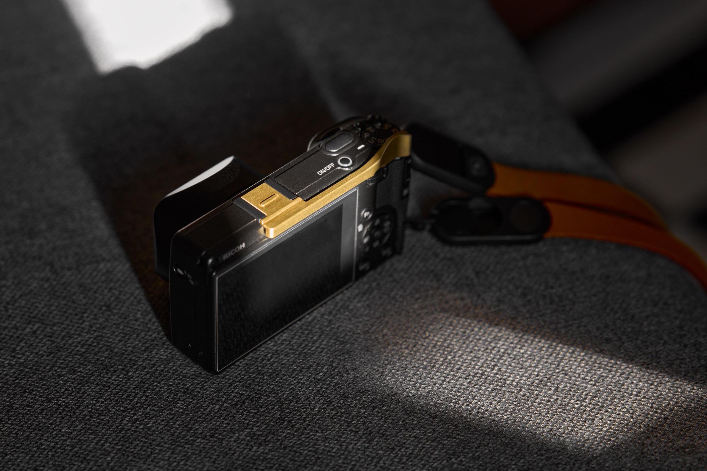 Ricoh GR IV camera with lens hood, thumb grip, and neck strap attached