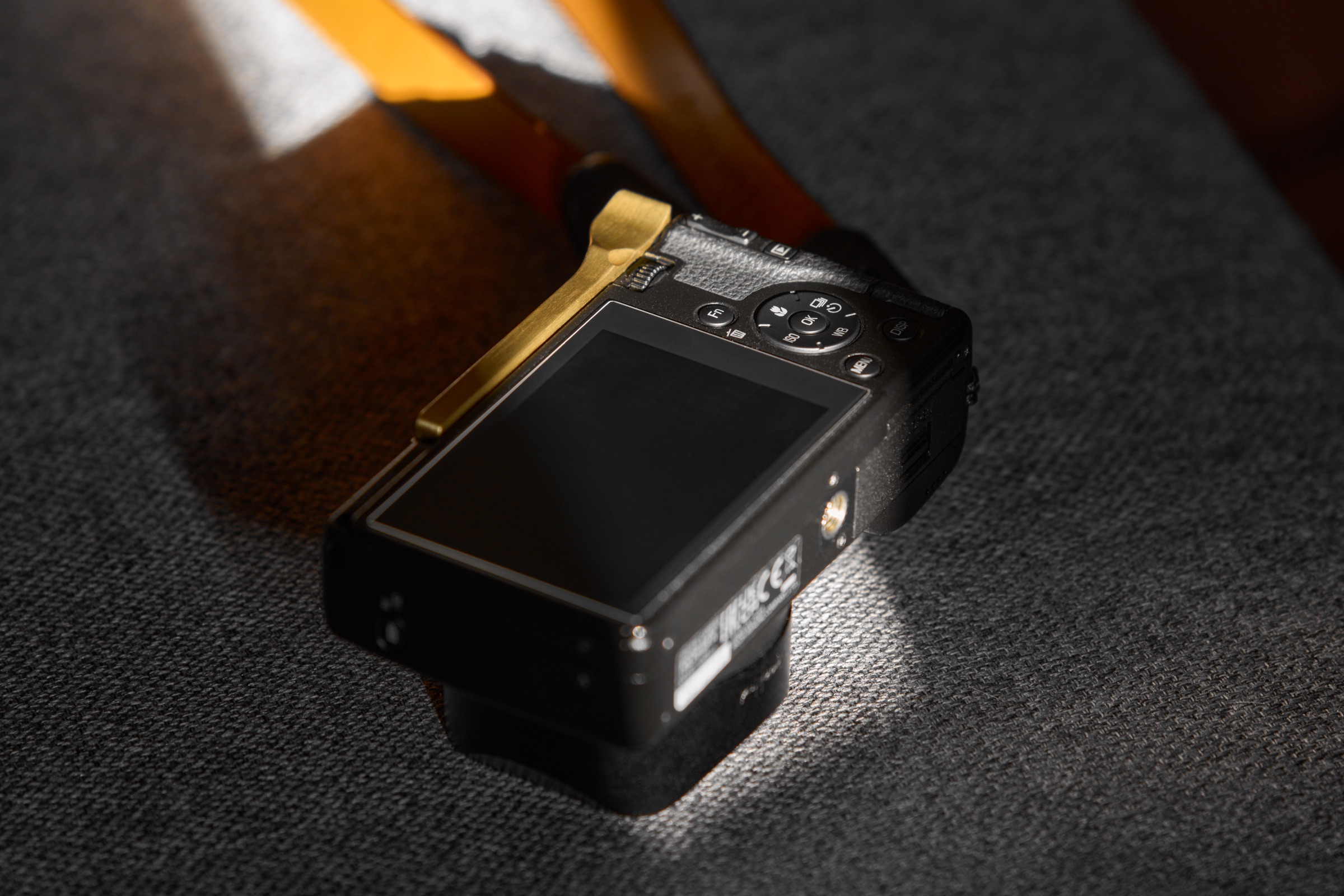Ricoh GR IV camera with lens hood, thumb grip, and neck strap attached
