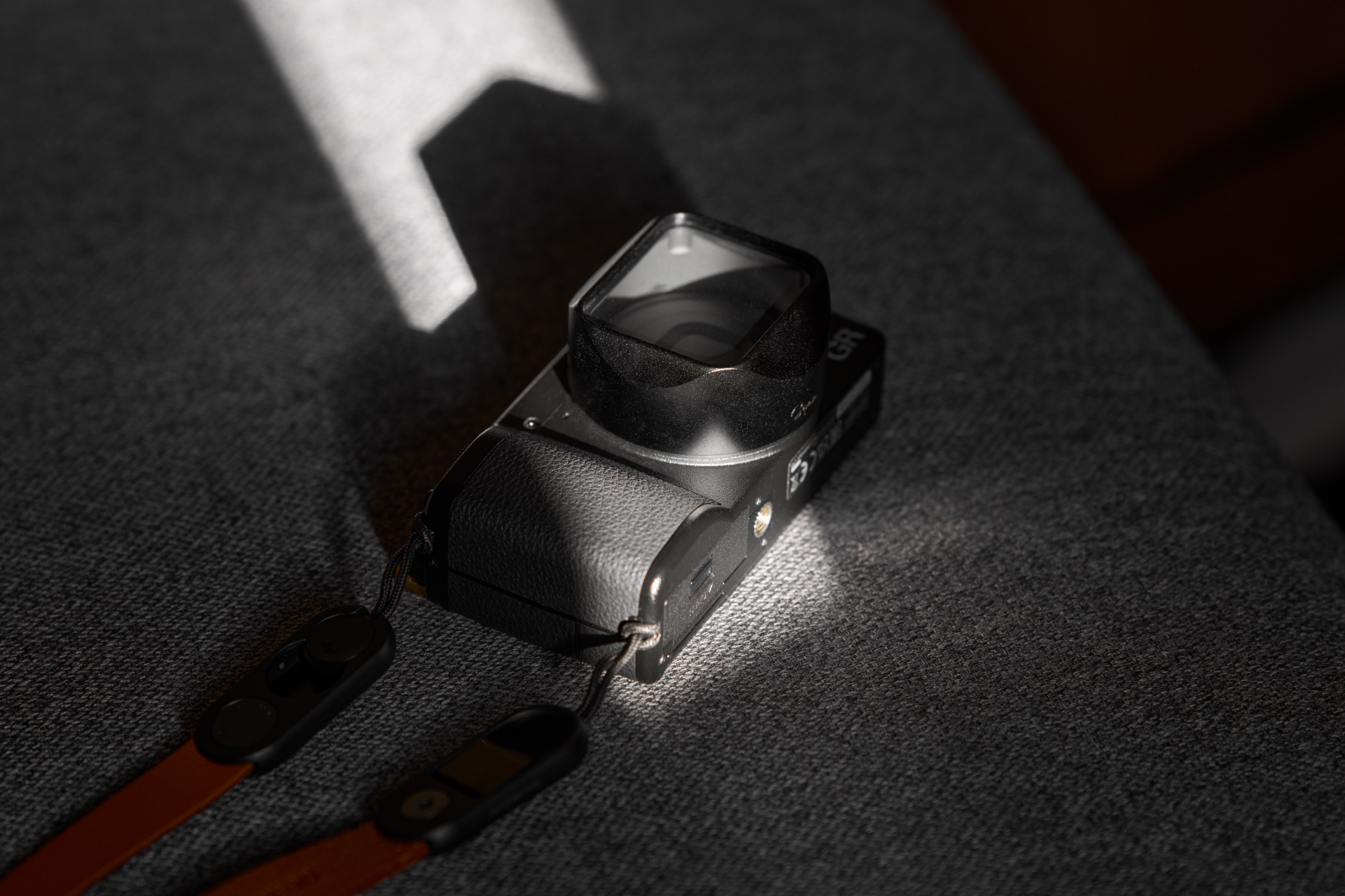 Ricoh GR IV camera with lens hood, thumb grip, and neck strap attached