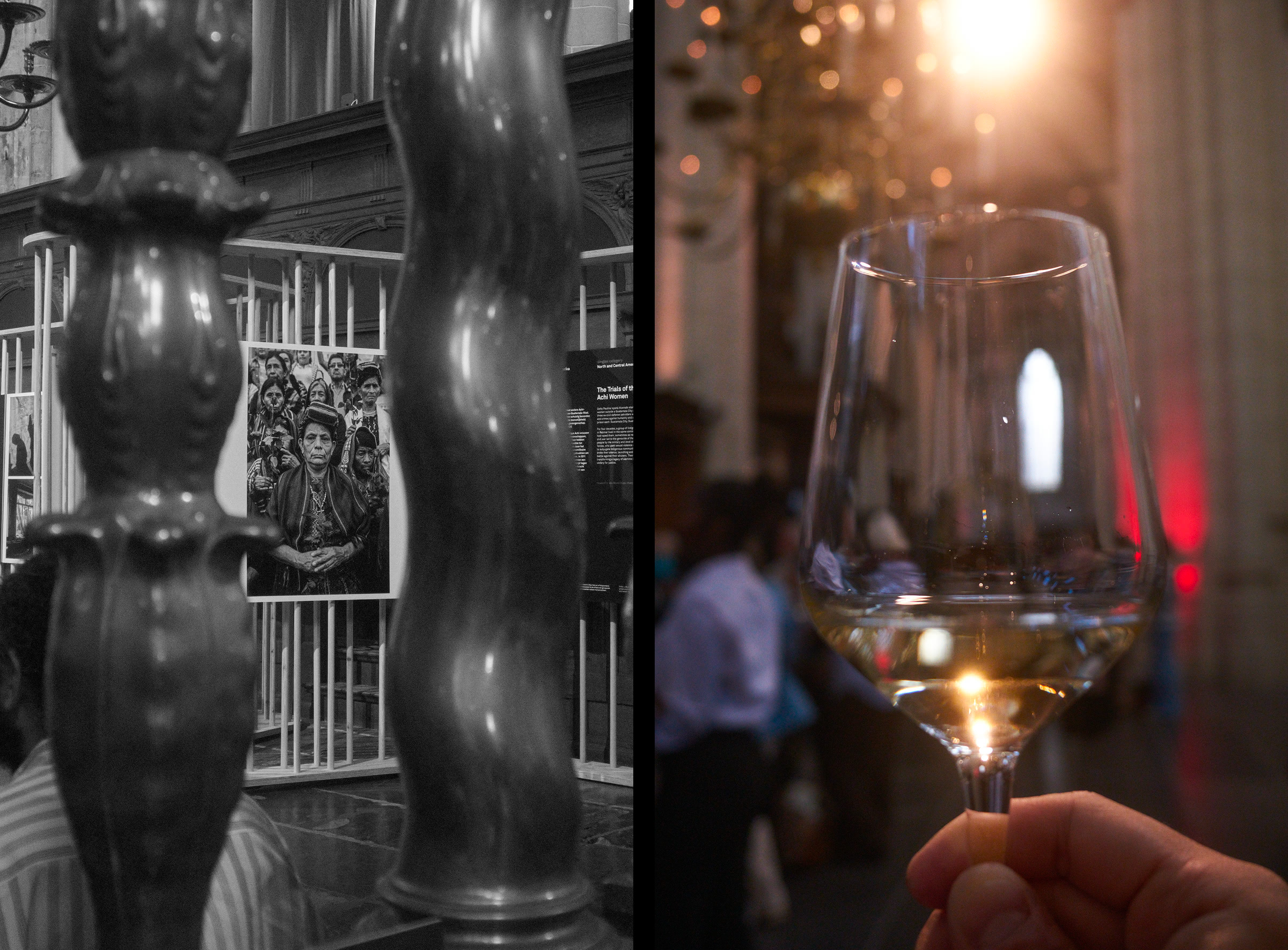 A hand holds a wine glass with a glowing light behind it. A portrait hangs in the background, partially visible through a gate. Dark, shallow depth of field.